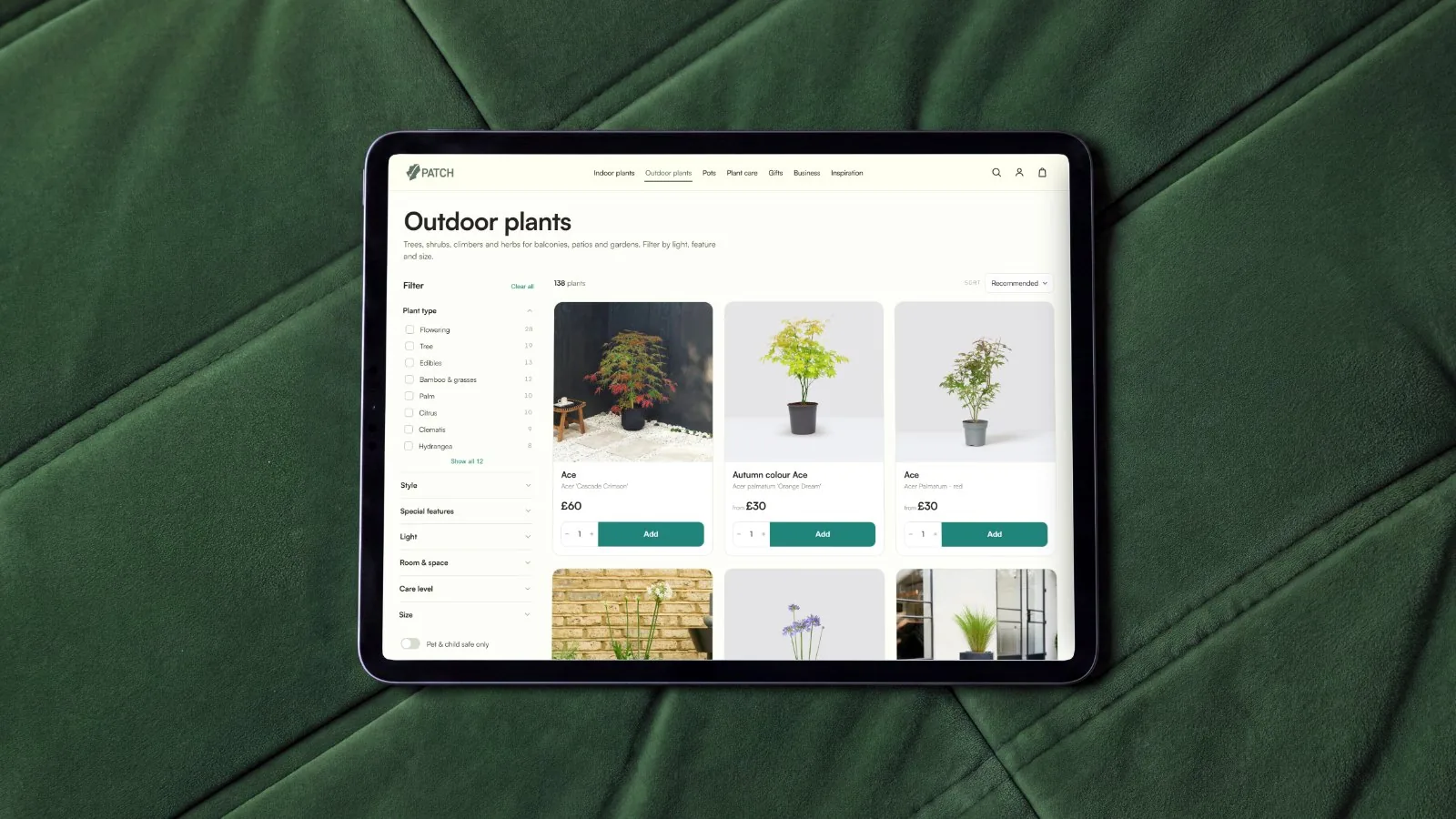 iPad on green velvet showing the Patch outdoor plants listing with filters and product cards