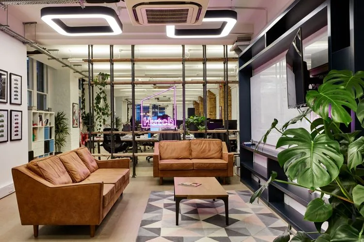 The Hutch games studio: leather sofas and a monstera beside a neon Hutch sign