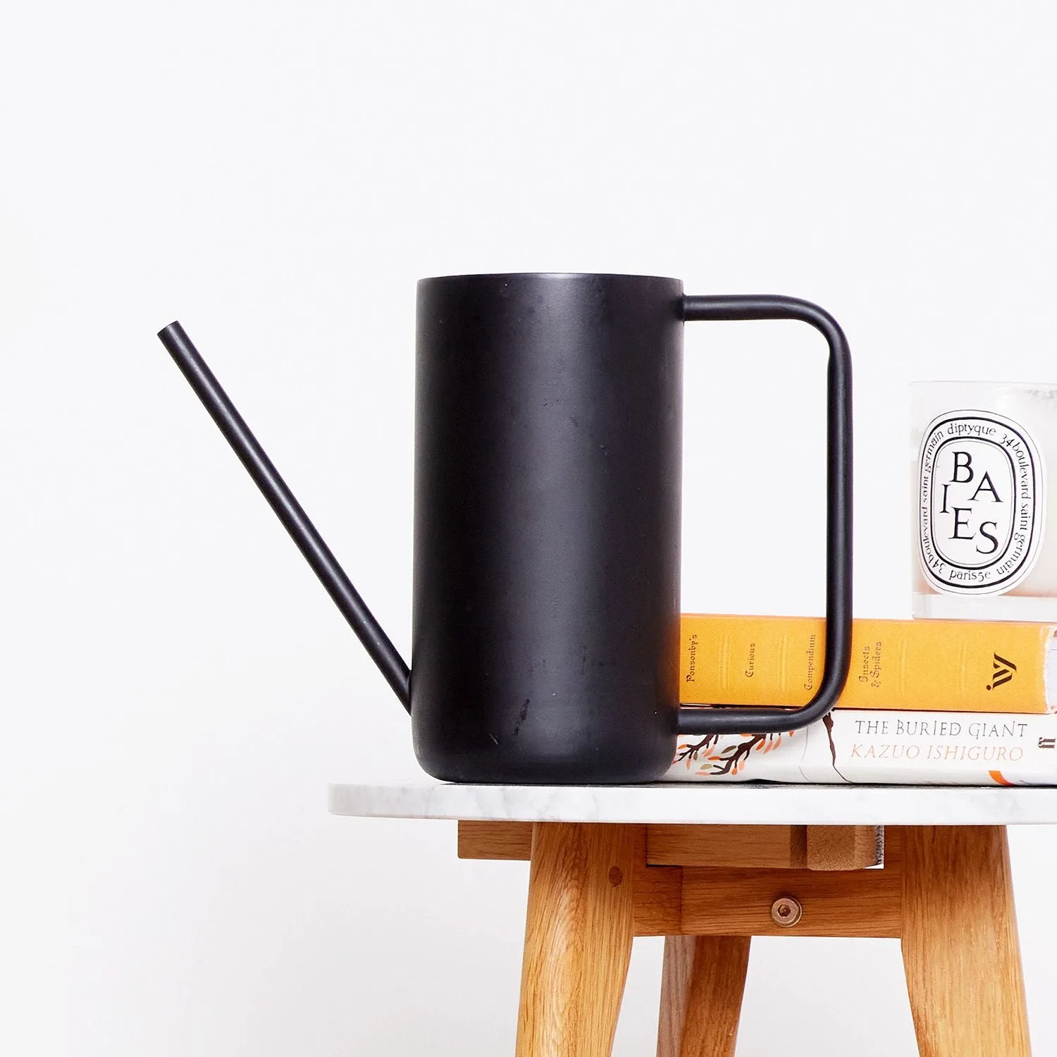 A black Patch watering can on a marble side table