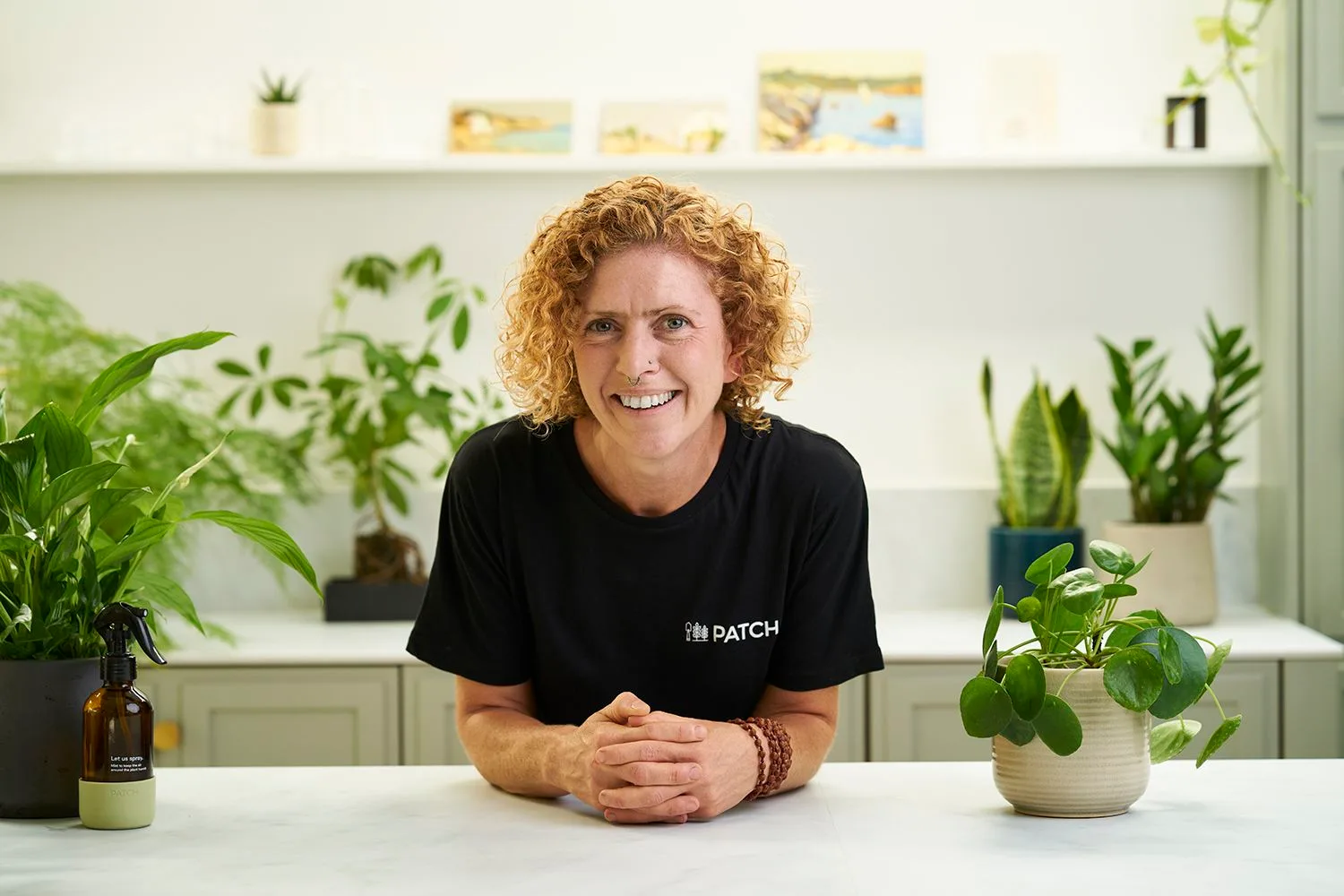 A Patch Plant Doctor at a bench surrounded by houseplants, ready to answer questions
