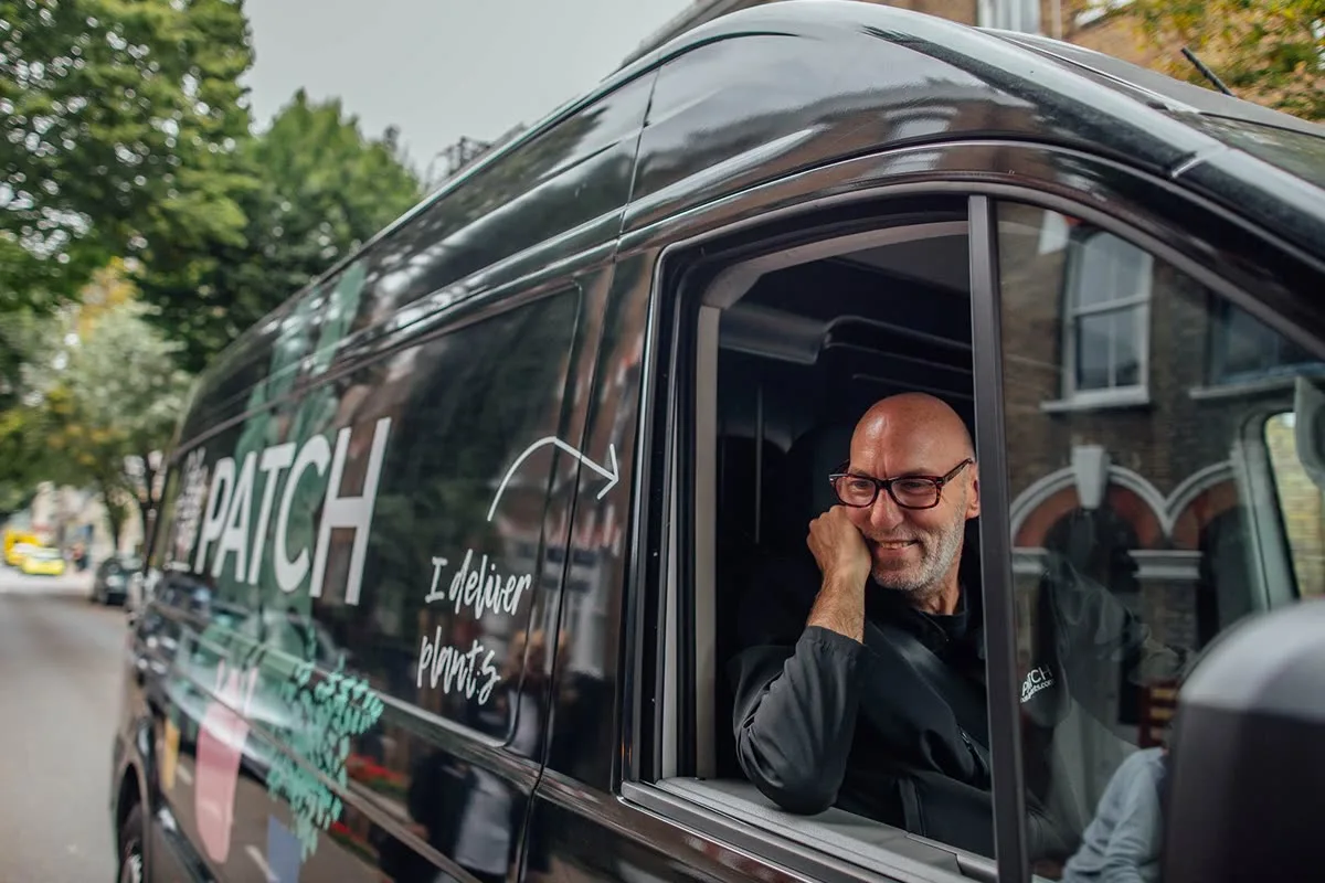 A Patch delivery driver with a black branded van